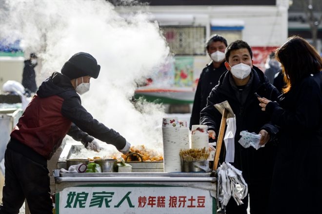 Des habitants d'Urumqi, capitale de la région du Xinjiang (nord-ouest), dans le nord-ouest de la Chine, achètent de la nourriture à un vendeur de rue le 1er décembre 2022