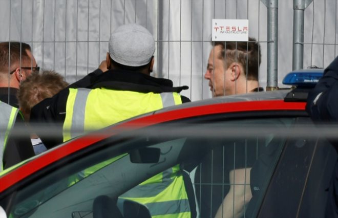 Le patron de Tesla Elon Musk (d) arrive à l'usine Tesla de Grünheide, près de Berlin, une semaine après un sabotage qui a entraîné l'arrêt de la production, le 13 mars 2024