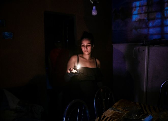 Une femme s'éclaire à la bougie pendant une coupure d'électricité, à la Havane, le 25 mai 2022