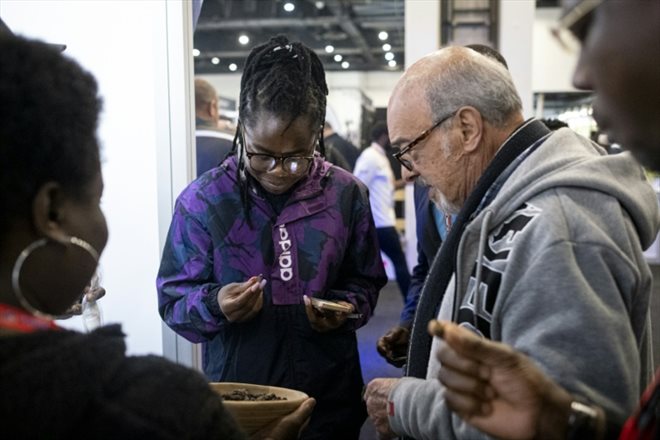 Des cients goûtent des chenilles mopanes séchées, lors d'un salon de l'alimentation dans le quartier d'affaires de Sandton, à Johannesburg, le 27 juin 2022