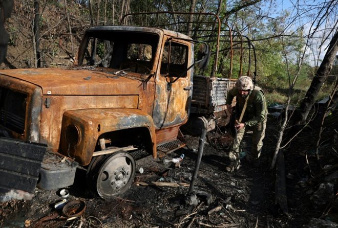 Un soldat ukrainien marche près d'un véhicule brûlé sur la ligne de front face aux troupes russes dans la région de Donetsk, dans l'est de l'Ukraine, le 23 septembre 2022