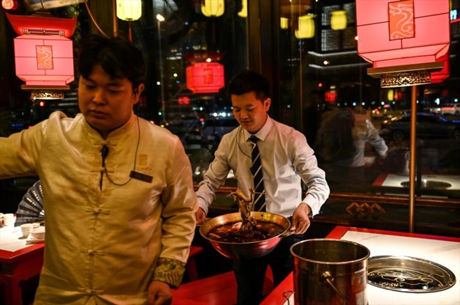 Un serveur emporte un pot de bouillon huileux, qui sera recyclé, dans un restaurant de fondue à Chengdu, dans la province du Sichuan, le 21 octobre 2023 en Chine