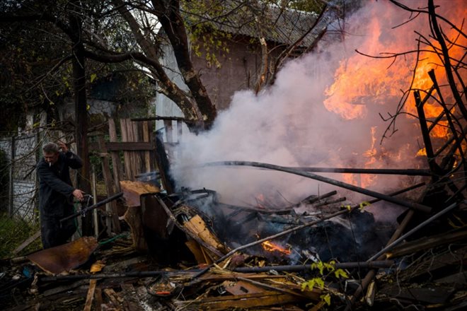 Un habitant tente d'éteindre un incendie après une frappe russe, le 23 octobre 2022 à Bakhmout, en Ukraine