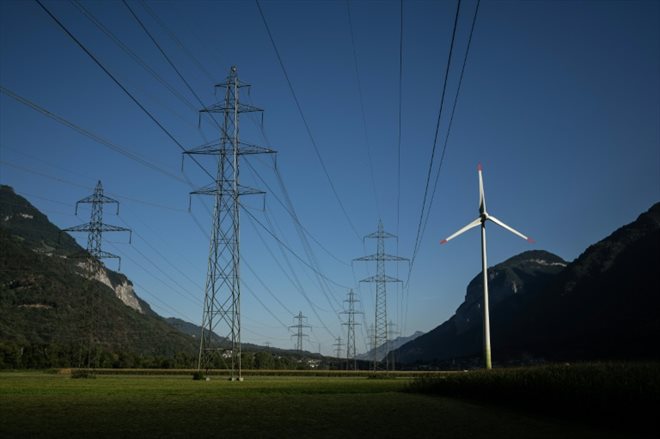 Un éolienne à proximité de pylones électriques près de Dorénaz, dans l'ouest de la Suisse, le 23 août 2022

