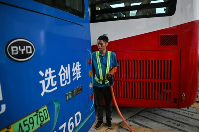 Un employé débranche le câble de recharge d'un bus électrique dans une  station de recharge à Shenzhen, le 18 octobre 2023 dans le sud de la Chine