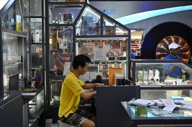 Le propriétaire chinois d'un magasin de réparation de téléphones portables, Chen Jing, au travail à Port Moresby, le 17 mai 2023
