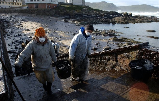 Des bénévoles évacuent des bassines de pétrole de la plage de Muxia, dans le nord-ouest de l'Espagne, affectée par la marée noire du Prestige le 23 novembre 2002