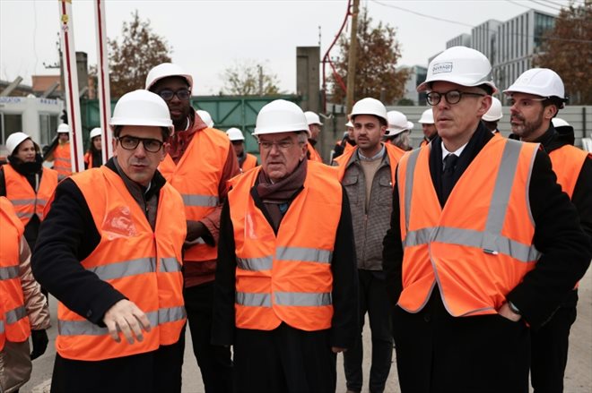 Nicolas Ferrand (à droite) accompagne le président du Comité international olympique Thomas Bach (au centre) et le maire de Saint-Denis Mathieu Hanotin (à gauche) sur le chantier du Village olympique le 1er décembre 2023 au nord de Paris