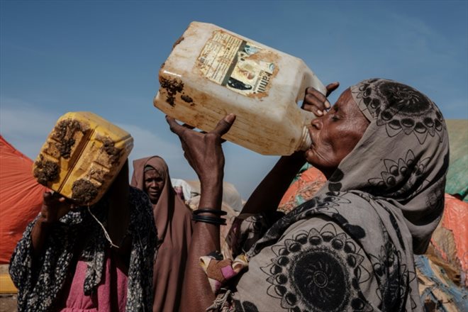 Une femme boit après une distribution d'eau dans le camp de déplacés de Muuri à Baidoa (Somalie) le 13 février 2022