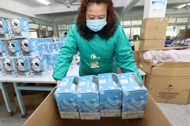 Une employée enfile des paquets dans une boîte pour l'expédition des mascottes Bing Dwen Dwen depuis l'usine de Nantong, le 8 février 2022 