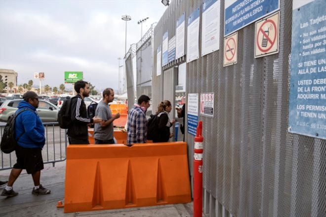 L'enseignant américain Gabriel Zarate (2e g), travaillant à San Diego, franchit la frontière pour rentrer chez lui à Tijuana, le 4 octobre 2022 au Mexique