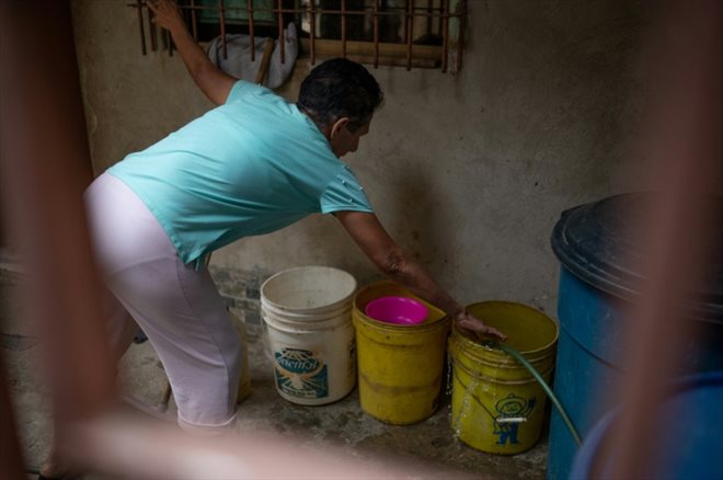 Une femme remplit des bidons d'eau dans sa maison de La Vega, à Caracas, le 9 août 2023 au Venezuela