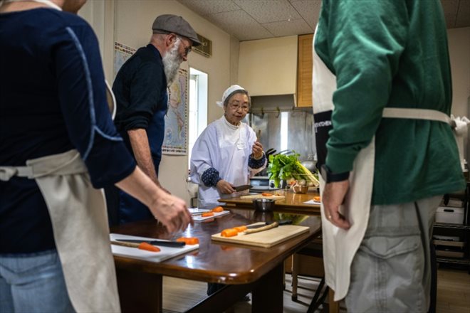Mari Fujii (c) montre comment préparer une soupe de légumes aux participants d'un cours intensif de cuisine bouddhiste végétarienne shojin, le 15 avril 2023 à Kamakura, au Japon