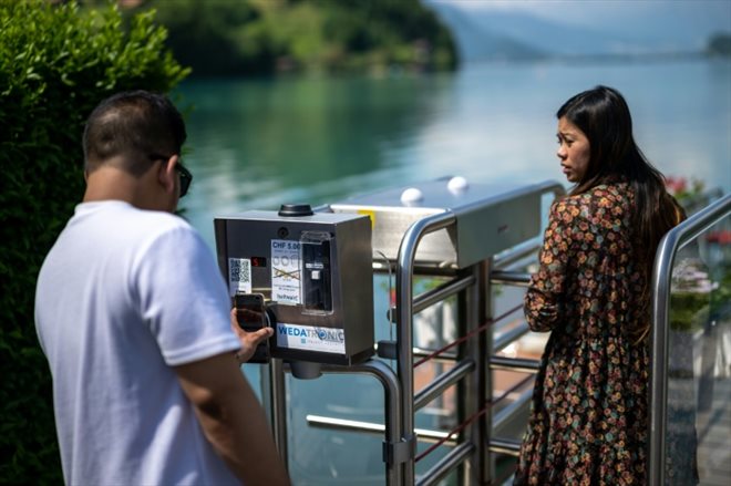 Un touriste paie avec son téléphone pour accéder à la jetée en bois rendue célèbre par une série Netflix sud-coréenne, le 2 juin 2023 à Iseltwald, en Suisse 