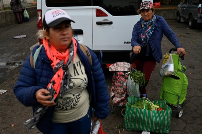 Limpia Benitez (d) et Gladys Meza g) repartent chargées de fruits et de légumes en bon état récupérés dans une benne à ordure du Marché central de Buenos Aires, le 9 juin 2023 en Argentine