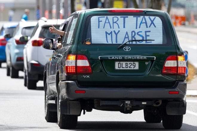 Taxe de pet, mon cul, peut-on lire sur une pancarte au dos d'une voiture lors d'une manifestation en Nouvelle-Zélande contre la taxation des pets des vaches et moutons le 20 octobre 2022