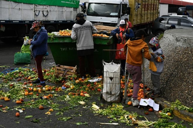 Limpia Benitez (g) et Gladys Meza (d)  récupèrent des fruits et des légumes en bon état dans une benne à ordure du Marché central de Buenos Aires, le 9 juin 2023 en Argentine