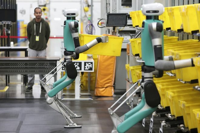 Des robots bipèdes déplacent des conteneurs lors d'un test de  manipulation mobile au centre de distribution BFI1 d'Amazon, le 18 octobre 2023 à Sumner