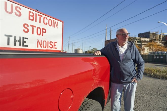 Bryan Maacks avec son panneau US Bitcoin Stop au bruit, à Niagara Falls dans l'Etat de New York, le 24 octobre 2022 