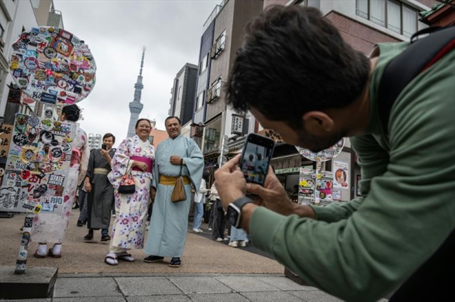 Des touristes en kimono se prennent en photo près du temple Sensoji à Tokyo le 30 Avril 2024 avec la tour de radiodiffusion Tokyo Skytree à l'arrière plan. Photo prise le 30 Avril 2024