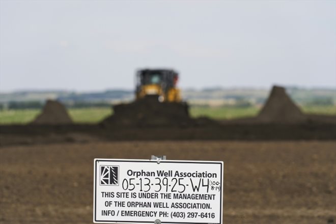 Une pancarte de l'association des puits orphelins pendant une opération d'assainissement sur le site d'un puits de pétrole orphelin, le 24 mai 2023 à Red Deer, dans la province de l'Alberta, au Canada