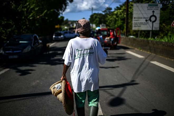Une femme porte un t-shirt portant le slogan Tous contre le chlordécone  à La Boucan à Sainte-Rose, sur l'île de la Guadeloupe, le 29 novembre 2021