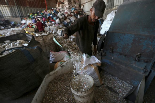 Un ouvrier palestinien prépare le plastique avant de la faire fondre pour en extraire du pétrole dans un atelier dans la bande de Gaza, le 23 août 2022