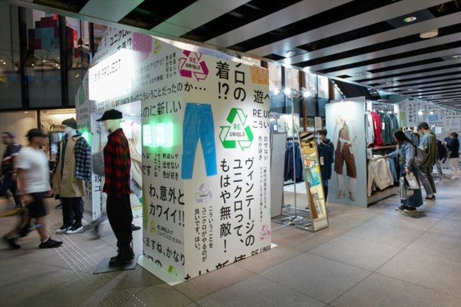 Des clients regardent, le 17 octobre 2023 à Tokyo, des vêtemments Uniqlo vendus dans un pop-up store de la célèbre marque japonaise