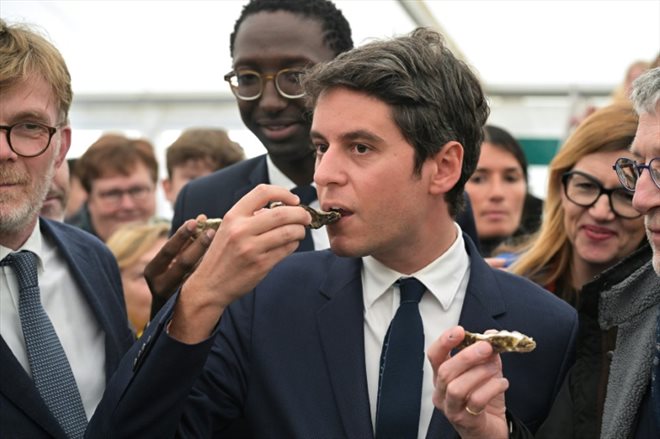 Le Premier ministre Gabriel Attal (centre), le ministre de l'Agriculture Marc Fesneau (gauche) et le secrétaire d'Etat à la Mer Hervé Berville (au second-plan), le 27 avril 2024 à la Foire aux Bulots de Pirou, dans le nord-ouest de la France