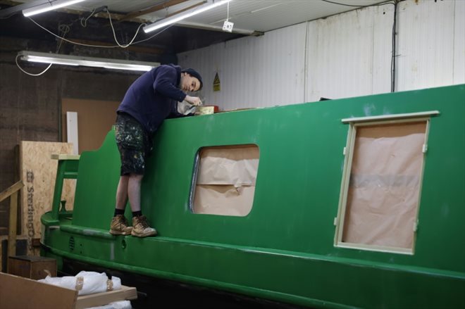 Un employé peint une péniche hybride dans l'atelier d'Ortomarine, une entreprise spécialisée dans la construction de péniches électriques, le 25 janvier 2024 dans le Worcestershire