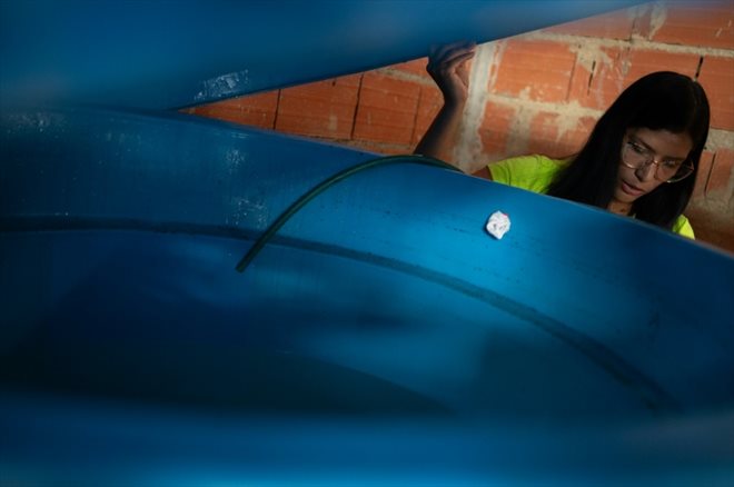 Yusmary Gomez soulève le couvercle du réservoir d'eau de sa maison dans le quartier de La Vega, à Caracas, le 9 août 2023 au Venezuela