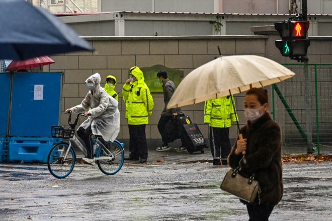 Des policiers (en jaune) surveillent la rue Wulumuqi, le nom en mandarin d'Urumqi, à Shanghai en Chine le 29 novembre 2022, après de récentes manifestations contre les restrictions anti-Covid