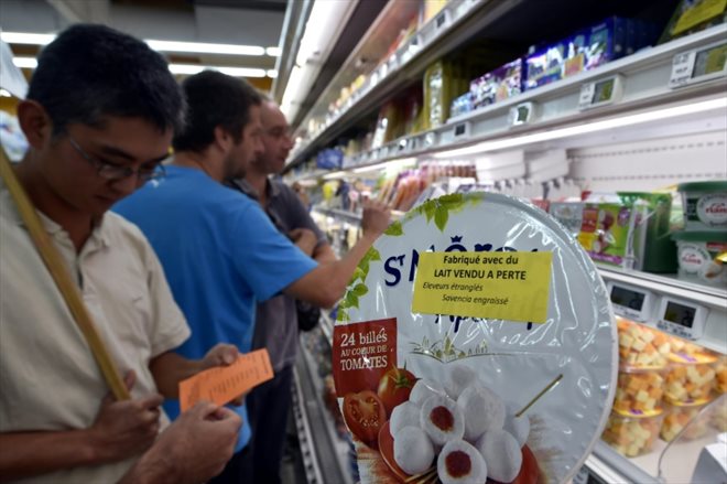 Des agriculteurs posent des étiquettes Fabriqué avec du lait vendu à perte sur un produit de du groupe agroalimentaire Savencia dans une grande surface de Rodez, en Aveyron, le 18 août 2015