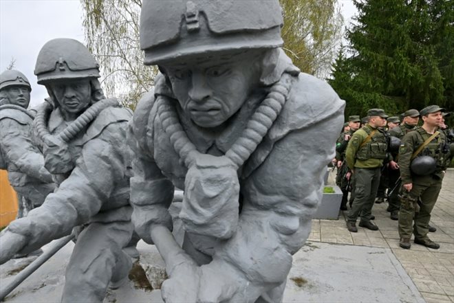 Soldats ukrainiens à côté d'une statue rendant hommage aux pompiers morts dans la catastrophe de 1986, le 26 avril 2022 