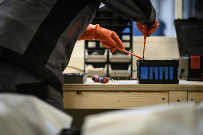 Un mécanicien travaille sur un module de batterie d'une voiture électrique, dans un garage spécialisé dans la réparation des voitures électriques, à Carquefou, dans l'ouest de la France, le 30 novembre 2022