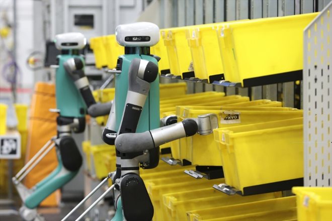 Des robots bipèdes déplacent des conteneurs lors d'un test de  manipulation mobile au centre de distribution BFI1 d'Amazon, le 18 octobre 2023 à Sumner