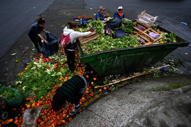 Limpia Benitez (d) et Gladys Meza (2e d)  récupèrent des fruits et des légumes en bon état dans une benne à ordure du Marché central de Buenos Aires, le 9 juin 2023 en Argentine