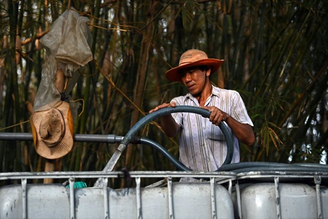 L'agriculteur Nguyen Van Hung remplit un réservoir d'eau fraîche pour la vendre, dans la province de Ben Tre, le 19 mars 20245 dans le sud du Vietnam