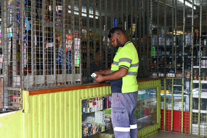 Un homme achète des marchandises dans un commerce protégé par des grilles en fer à Port Moresby, le 18 mai 2023
