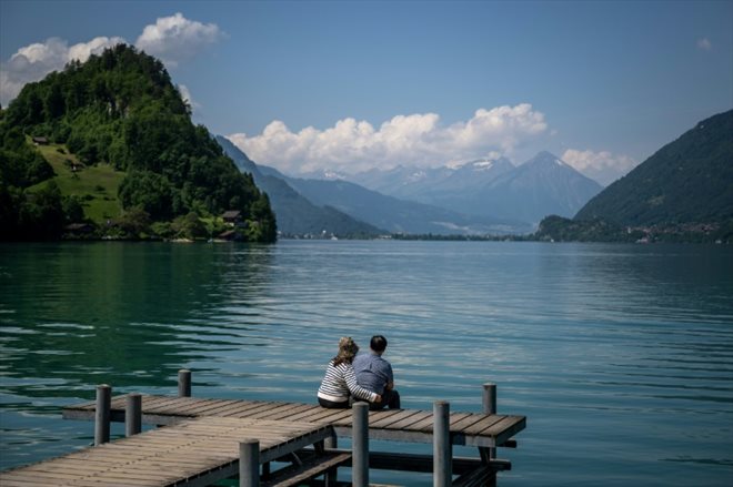 Un couple de touristes assis sur la jetée en bois rendue célèbre par une série Netflix sud-coréenne, le 2 juin 2023 à Iseltwald, en Suisse