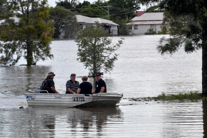 Des habitants en bateau dans une rue inondée à Lawrence, à quelque 70 km de la ville de Lismore, en Nouvelle-Galles du Sud, le 2 mars 2022