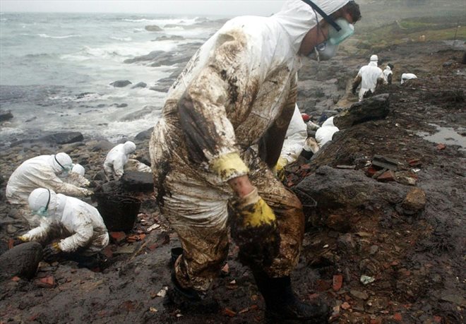 Des bénévoles tentent de nettoyer la plage de Muxia, dans le nord-ouest de l'Espagne, polluée par la marée noire du Prestige le 1er décembre 2002