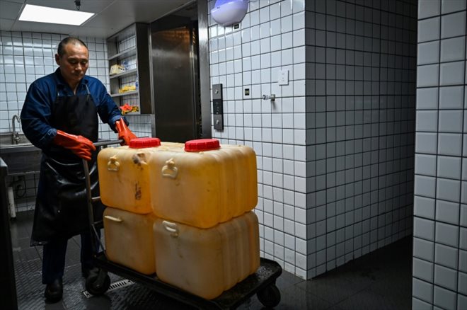 Un agent de collecte transporte de l'huile usagée récupérée dans un restaurant de fondue de Chengdu qui sera recyclée pour produire du carburant, le 21 octobre 2023 dans la province du Sichuan, en Chine