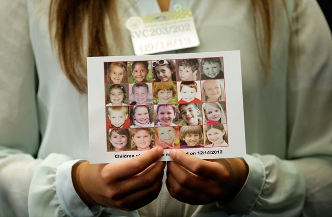 Une femme montre les portraits des victimes de la tuerie de l'école de Sandy Hook, le 17 septembre 2013 à Washington