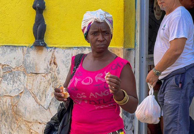 Une Cubaine mange une portion de pain devant une boulangerie, le 17 septembre 2024 à La Havane