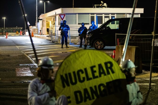 Des gendarmes en position derrière des militants de Greenpeace qui bloquent l'entrée du chantier du réacteur EPR à Flamanville, le 31 mars 2022 dans la Manche