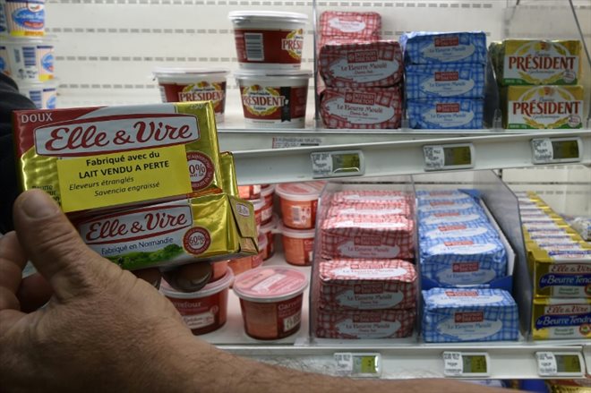 Des agriculteurs posent des étiquettes Fabriqué avec du lait vendu à perte sur un produit de du groupe agroalimentaire Savencia dans une grande surface de Rodez, en Aveyron, le 18 août 2015