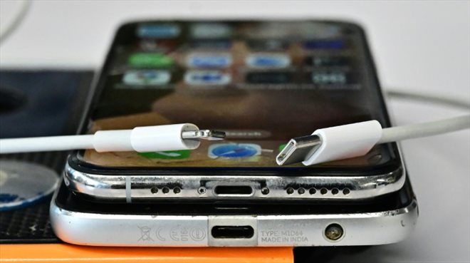 Un chargeur USB-C (d) et un chargeur Lightning d'Apple (g) sur un iPhone et un smartphone Androide superposés, le 11 septembre 2023 à Los Angeles