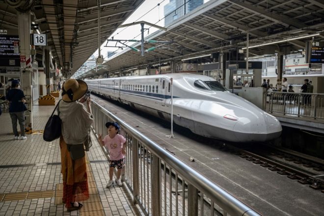 Une femme photographie son enfant devant un train à grande vitesse Shinkansen, à la gare de Tokyo, le 25 juillet 2024