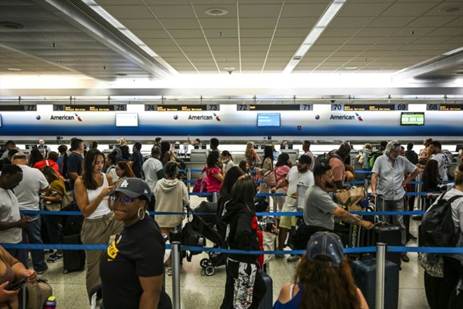 Des voyageurs font la queue à un comptoir d'enregistrement à l'aéroport de Miami, pendant une panne informatique mondiale, le 19 juillet 2024 en Floride